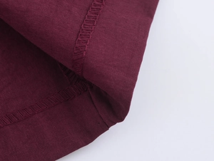 Close-up detail of burgundy straight trousers fabric texture and reinforced double stitching