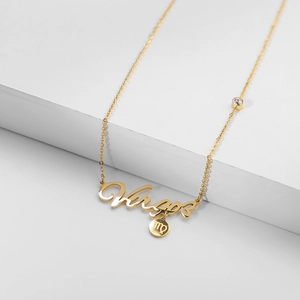 Detailed shot of golden Virgo zodiac necklace with script pendant and small charm