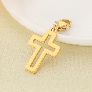 Close-up of a gold hollow cross pendant with lobster clasp on beige textured fabric