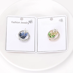 Detailed view of wheat-shaped brooches with blue and green crystals on a round frame