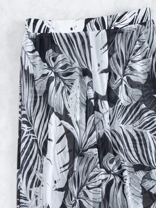 Detail of sheer mesh beach trousers featuring tropical leaf prints in black and white