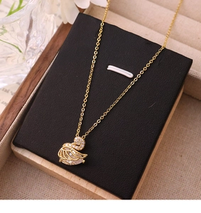 Macro view of gold swan pendant necklace featuring white zircon and a pear-cut main stone