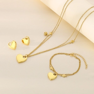 Detailed set of 18K gold plated heart necklace, bracelet and earrings on soft fabric