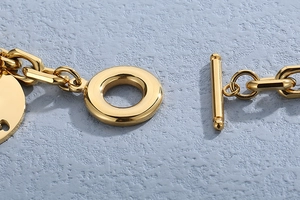 Close-up of gold OT buckle and heart-hollow round pendant on minimalist stainless steel bracelet