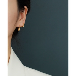 Close-up of gold S925 silver earrings with three zircon tassels worn by a model