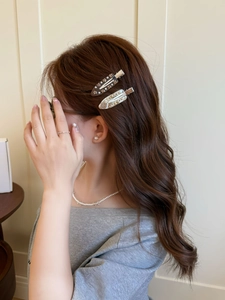 Détail de barrettes françaises en acétate avec cristaux sur cheveux bruns ondulés