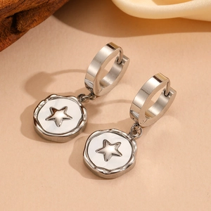 Macro shot of silver stainless steel hoop earrings with star cutout pendant on wood background