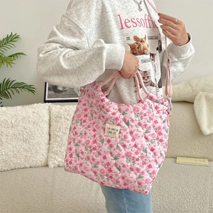 Sac à bandoulière matelassé rose à fleurs présenté dans un intérieur chaleureux