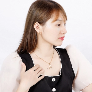 Elegant gold letter S necklace and stud earrings set with white crystals on a female model