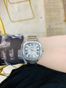 Detail of silver rectangular women's watch with white roman dial and metal strap