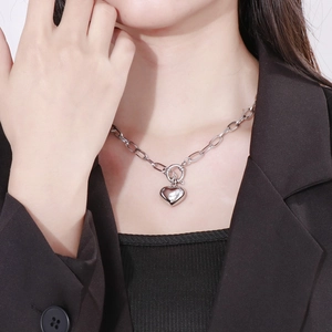 Detail shot of silver chunky chain necklace with heart pendant on model neckline