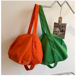 Detail of orange and green nylon tote bags with premium woven texture on metal stands
