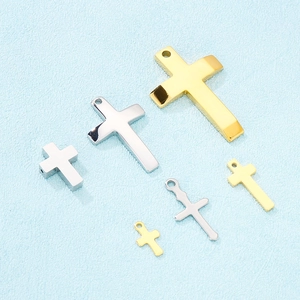 Polished stainless steel cross pendants in gold and silver finishes on light background