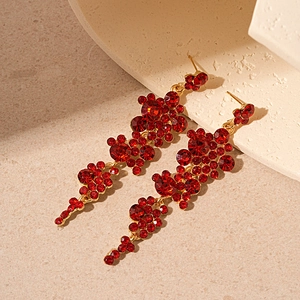 Detail of red rhinestone fringe drop earrings on a warm stone display background