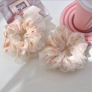 Macro detail of floral mesh scrunchies featuring organza layering and pink flower patterns