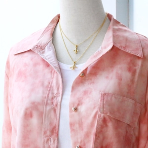 Detail of layered gold airplane pendant necklace styled on bead chains for women