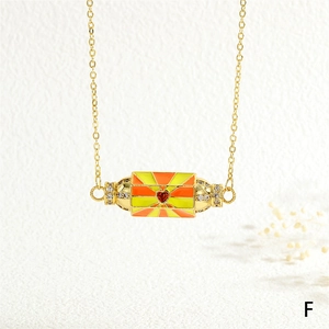 Detailed macro view of gold-tone necklace with orange enamel pendant and red heart stone