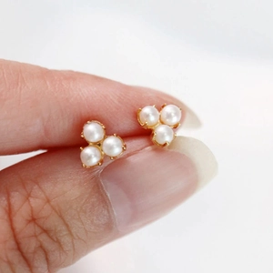 Detailed close-up of S925 sterling silver pearl cluster earrings with gold claw settings