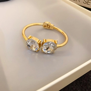 Detail of gold teardrop cuff bracelet featuring two large faceted white crystals in a tray