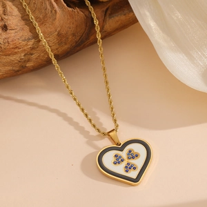 Détail du collier cœur en or avec trèfle de gemmes bleues sur de la soie blanche et bois