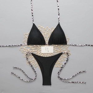 Close-up of black bikini set with leopard print straps on a stylish gold coaster