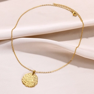 Détail du collier plaqué or 18 carats avec pendentif martelé sur tissu de soie doux