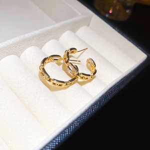 Close-up of gold chain link earrings with zircon stones on white velvet background