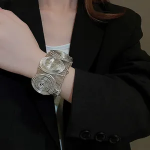 Artistic silver wide wire-wrapped bracelet with triple spiral design on model's wrist