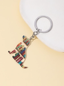 Detail of a cat shaped acrylic keychain featuring a stack of books on a stone pedestal