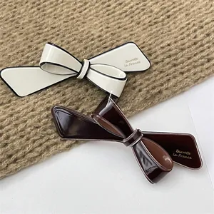Detailed close-up of French vintage bow hair clips in cream and coffee resin colors