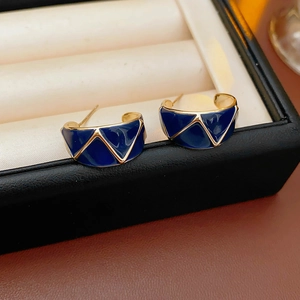 Macro shot of vintage blue enamel C-shaped earrings in a gold finish jewelry box