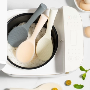 Food-grade silicone rice spoons in grey and yellow standing in a white rice cooker