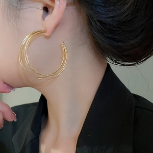 Nahaufnahme goldener mehrlagiger C-förmiger Creolen, die Stil und Größe zeigen