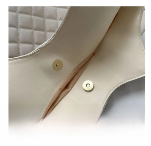 Gros plan du fermoir magnétique et de la texture matelassée d'un sac beige