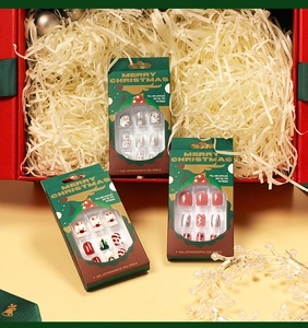 Close-up of Christmas press-on nails with snowman and reindeer designs in a festive gift box