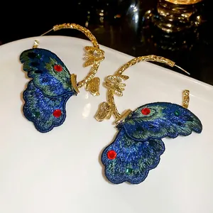 Vintage style gold hoops featuring intricate blue embroidered butterfly wings with crystals