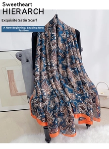 Detail of blue paisley silk scarf with contrasting orange borders and smooth satin texture