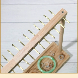 Detailed top view of wood jewelry display stand with gold metal hooks and storage tray