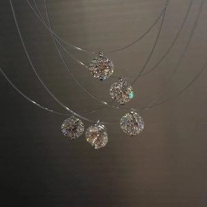 Dettaglio macro di pendenti tondi in zircone con castone a quattro griffe su fili da pesca