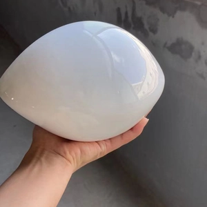 Dettaglio di un ornamento in ceramica bianco lucido a forma di uovo tenuto da una mano