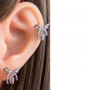 Detail of silver bow earrings with a pink teardrop-shaped zircon gemstone pendant