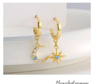 Detailed macro view of gold asymmetric moon and star earrings with micro inlaid zirconium