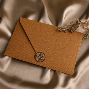 Detail of a brown embossed envelope with a round seal on a luxury silk background