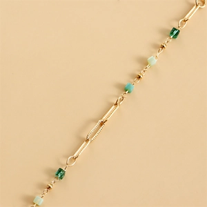 Close-up of golden metal chain with green square beads for eyewear or masks