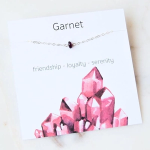 Detail of garnet gemstone pendant on gold chain with friendship message card