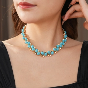 Gros plan d'un collier vintage doré avec pierres turquoise et petits strass brillants