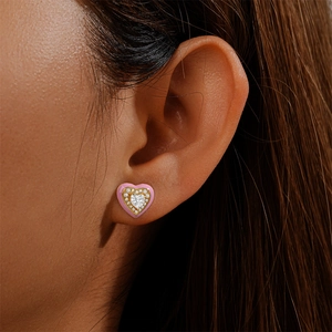 Close-up of pink enamel heart earring with sparkling center stone on a model's ear