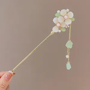 Detail of gold hair stick with white magnolia flowers, green leaves and tassel