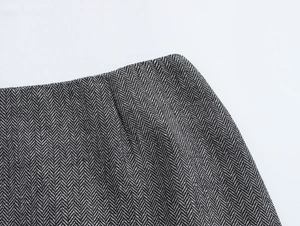 Close-up of black and white herringbone wool fabric and neat stitching on skirt waist