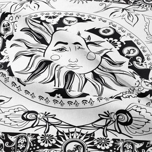 Close-up of bohemian sun and zodiac sign print on soft black and white textile fabric